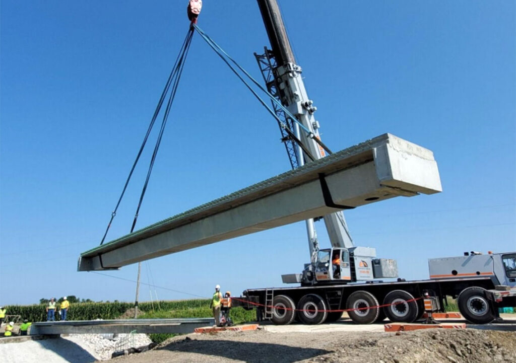 Crane hoisting a Valmont's U-BEAM Complete Bridge Solution beam